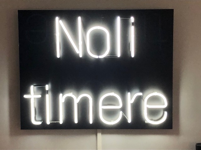 A sign with white lights that read Noli Timere