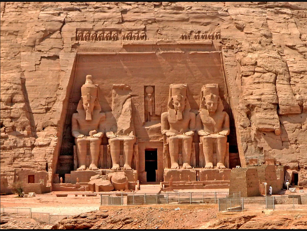 A stone temple with statues in front of it.